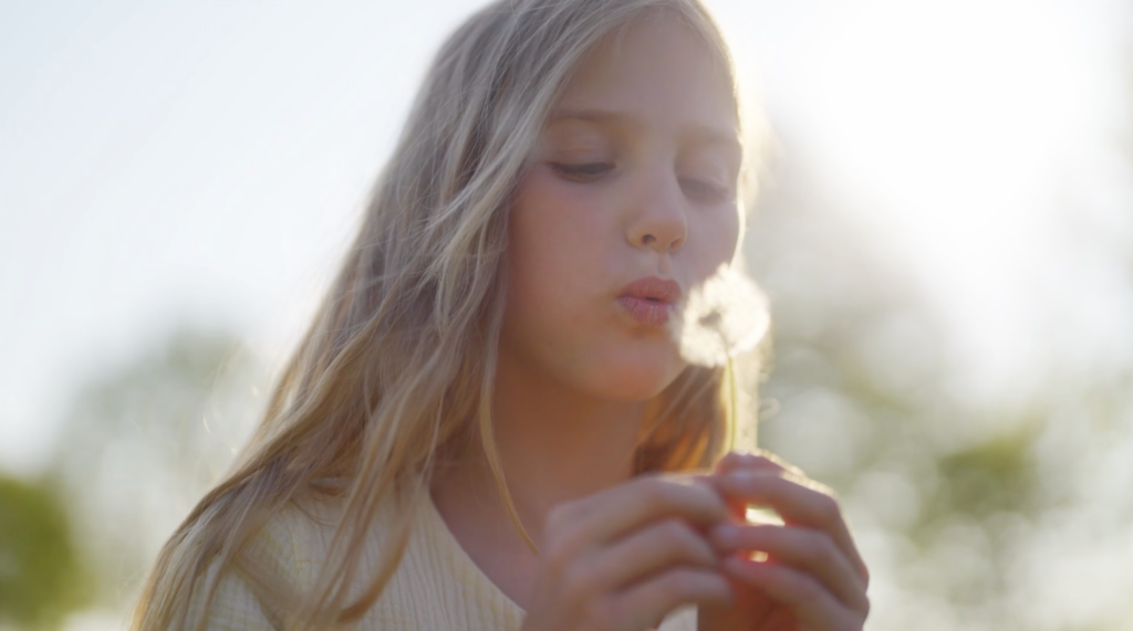 Meisje blaast op bloem